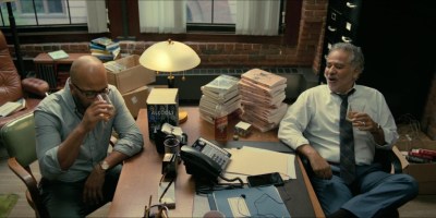 Scene from American Fiction 2023 movie with Thelonius "Monk" Ellison and his agent surrounded by books talking with book publishers over phone.