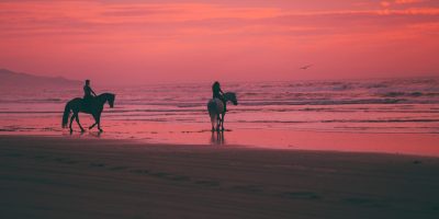 vibrance photo of man and woman on horses by beach. Cormac McCarthy Blood meridian. Photo by Austin Neill on Unsplash