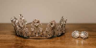 crown and earrings placed on wooden table