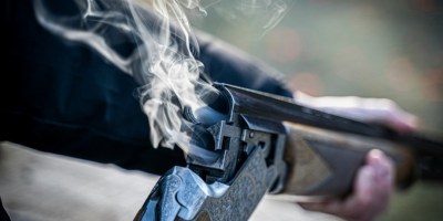 Man holding smoking rifle. Photo by Paul Einerhand on Unsplash