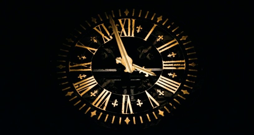 Black clock with gold hands to illustrate "Death Becomes Her" by Leah Fisher