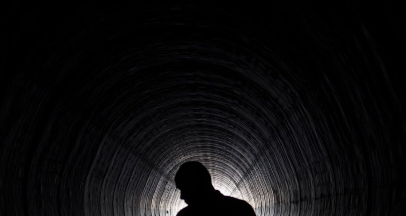 silhouette of man standing in tunnel